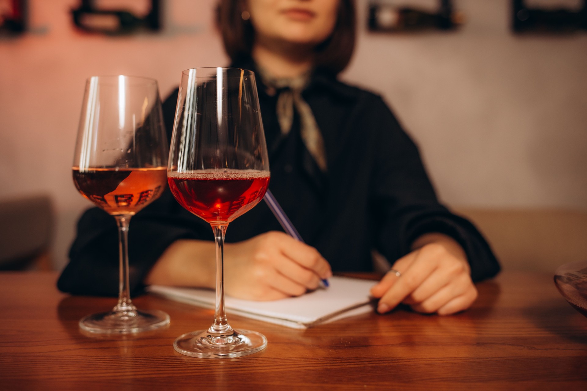 Extreme close up of female hand taking notes at red wine tasting.